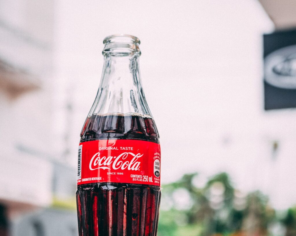 A close-up of an open Coca Cola bottle outdoors.