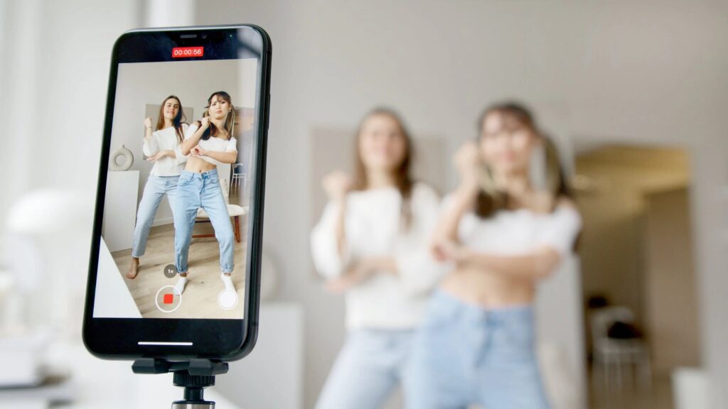 Two women recording a dance routine on a smartphone.